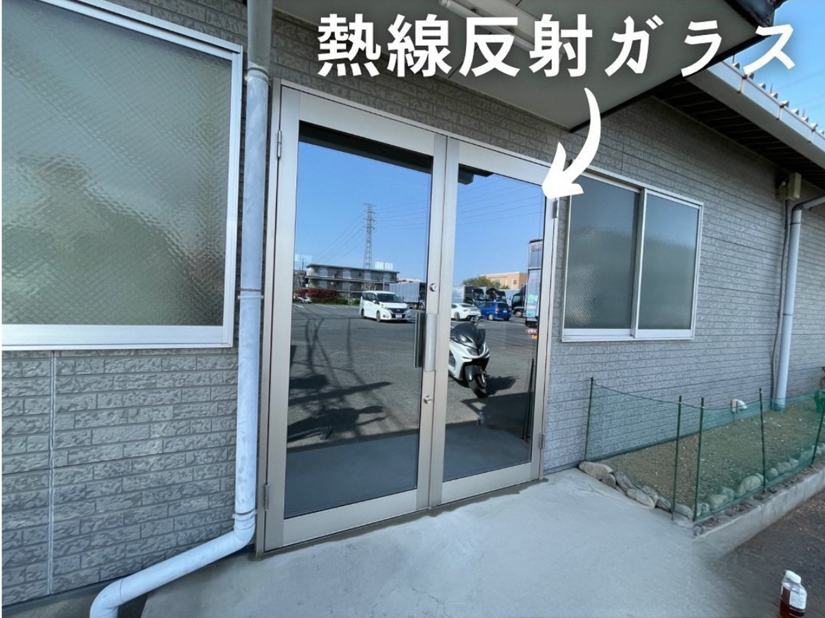 熱線反射ガラスを入れたアルミの店舗ドア(両開き)。ガラスが鏡のように外の景色を映している施工後の様子
