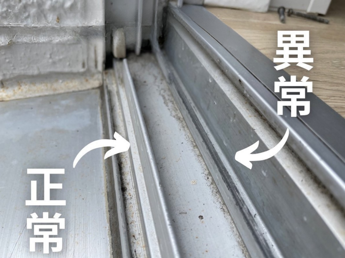 戸車の破損でアルミのレールが削れ、黒い筋と細かな削りカスが出ている様子